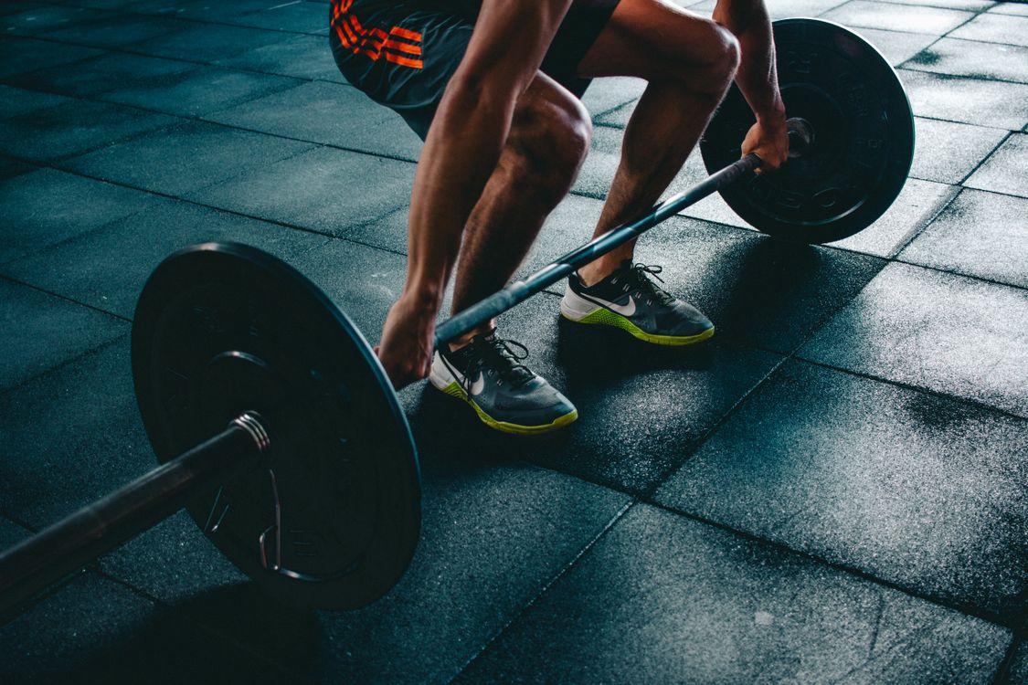 Person performing a barbell squat in a training space